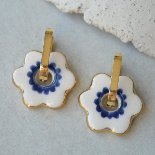Pair of floral hair clips with blue center and gold accents on a light gray background